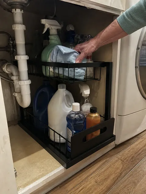Black organizer in a utility sink cabinet