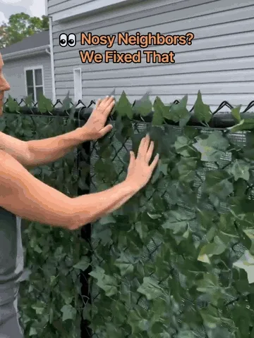 Artificial ivy privacy screen being unrolled and fastened to a fence