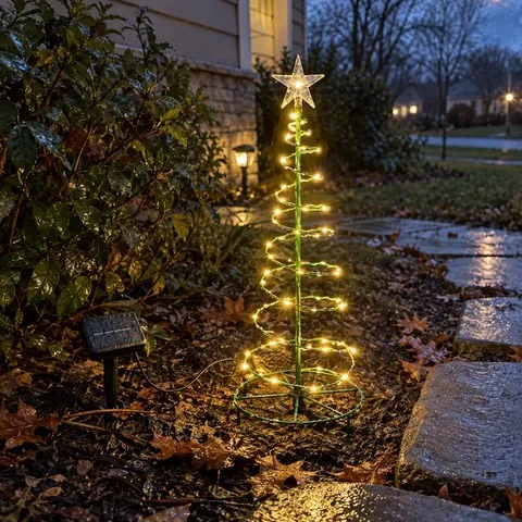 Warm-white spiral tree light glowing beside wet garden stones