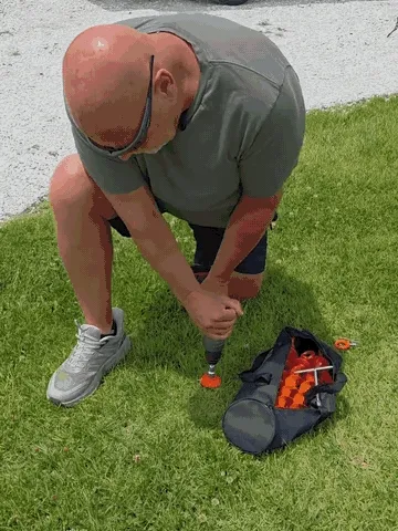 Twisting an orange full-spiral ground anchor into a lawn