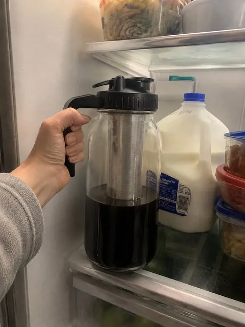 Cold-brew pitcher being placed on a refrigerator shelf
