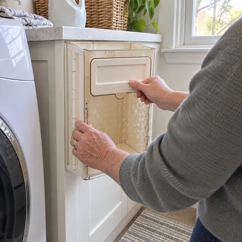 Cream white foldable bin being folded in a laundry room