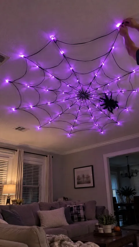 Purple spider web lights being adjusted on a living room ceiling