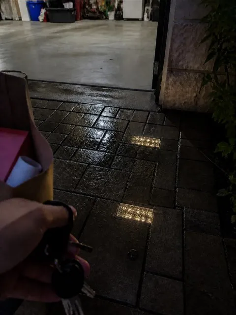 Warm glass brick lights glowing on damp driveway pavers