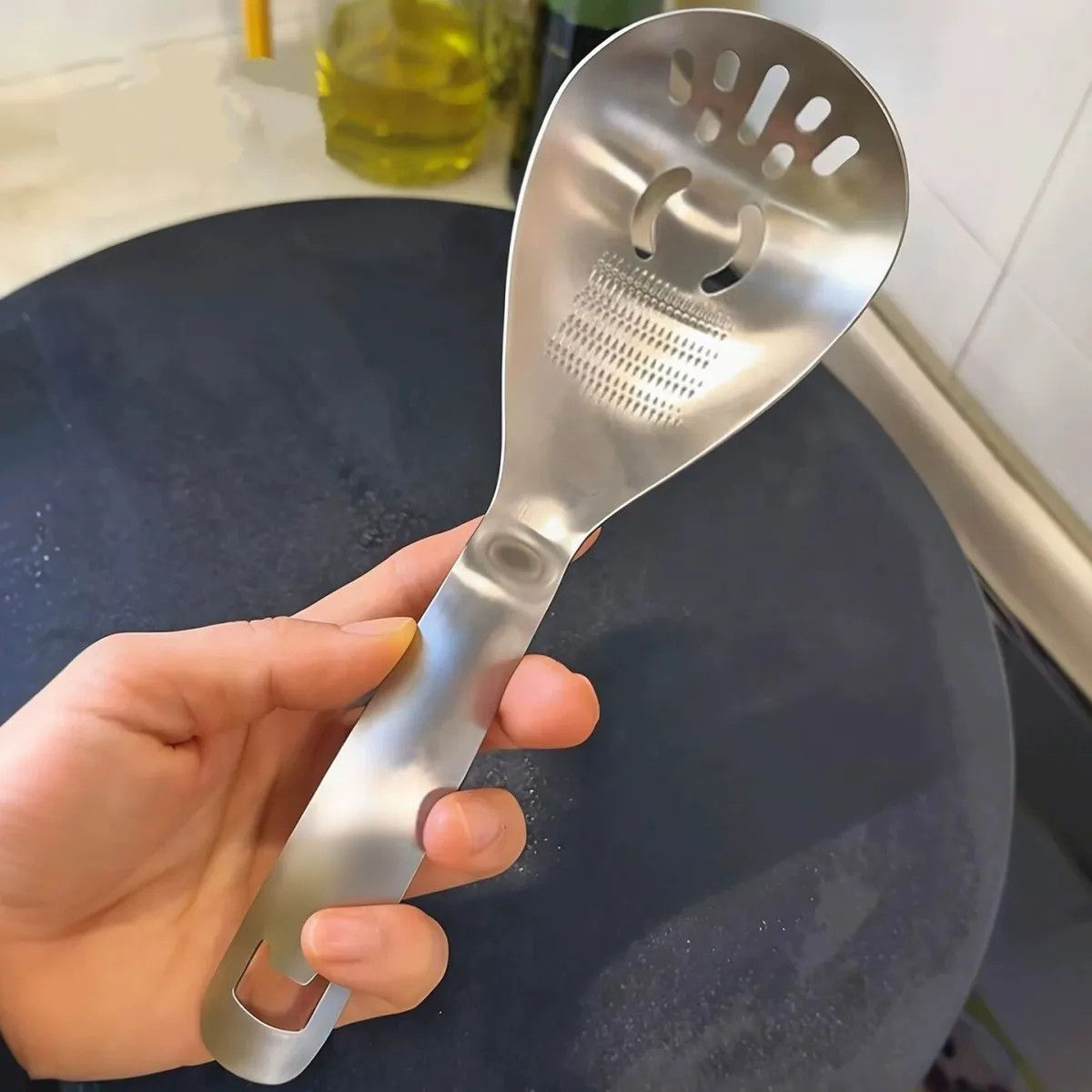 Die Ingwer- und Knoblauchreibe in der Hand, mit sichtbarer Reibfläche