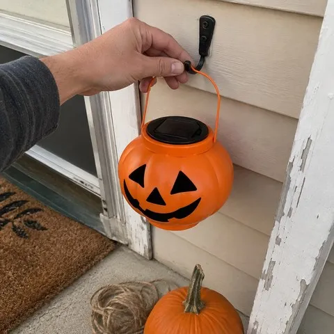 Pumpkin solar lantern being hung beside a front door