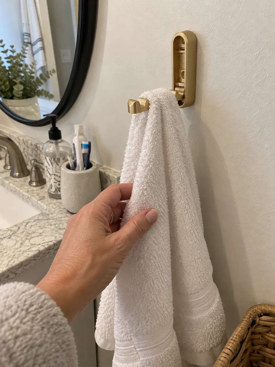 Gold folding hook holding a hand towel beside a bathroom sink