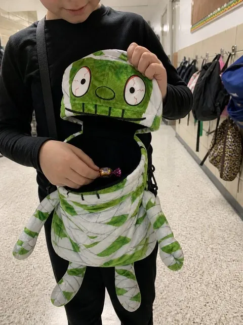 Child using a mummy treat bag after a school Halloween party