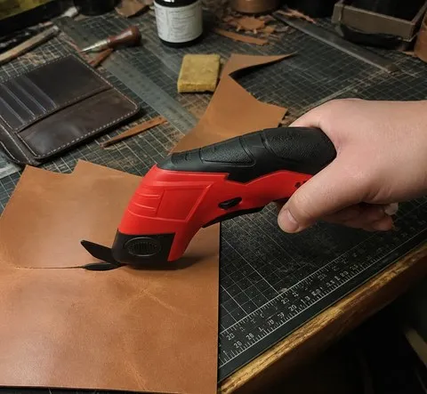 Red electric scissors on a leathercraft workbench