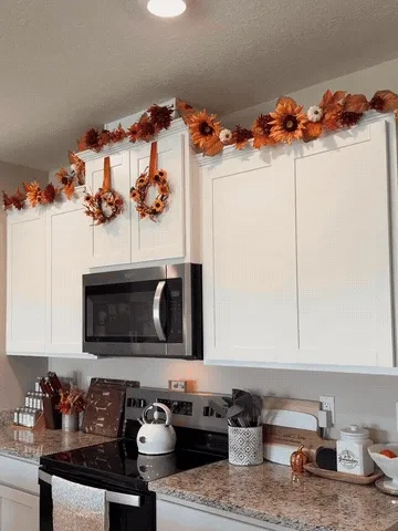 Fall garland being arranged around kitchen cabinets