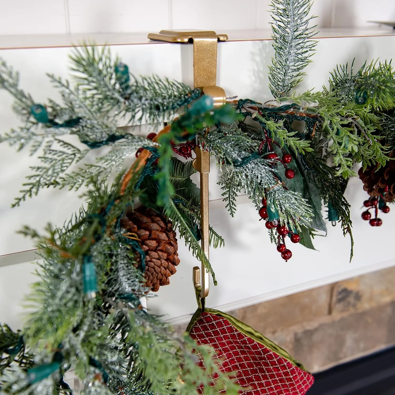 Adjustable mantel hanger holding garland and stockings on a fireplace mantel