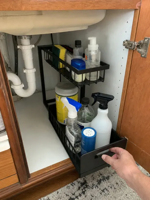 Black organizer pulled forward in a kitchen sink cabinet