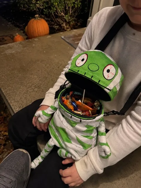 Mummy crossbody bag holding wrapped Halloween candy on a porch