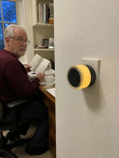 A black plug-in doorbell chime glowing near a home office
