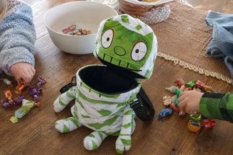 Children sorting wrapped candy around an open mummy treat bag