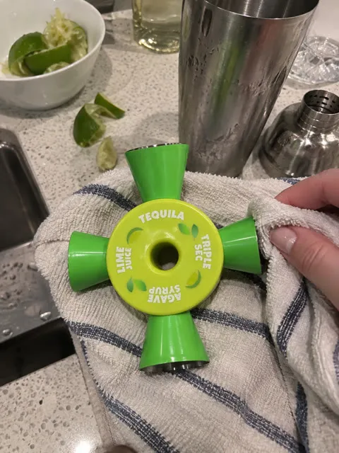 Four-way cocktail jigger being wiped dry after making drinks