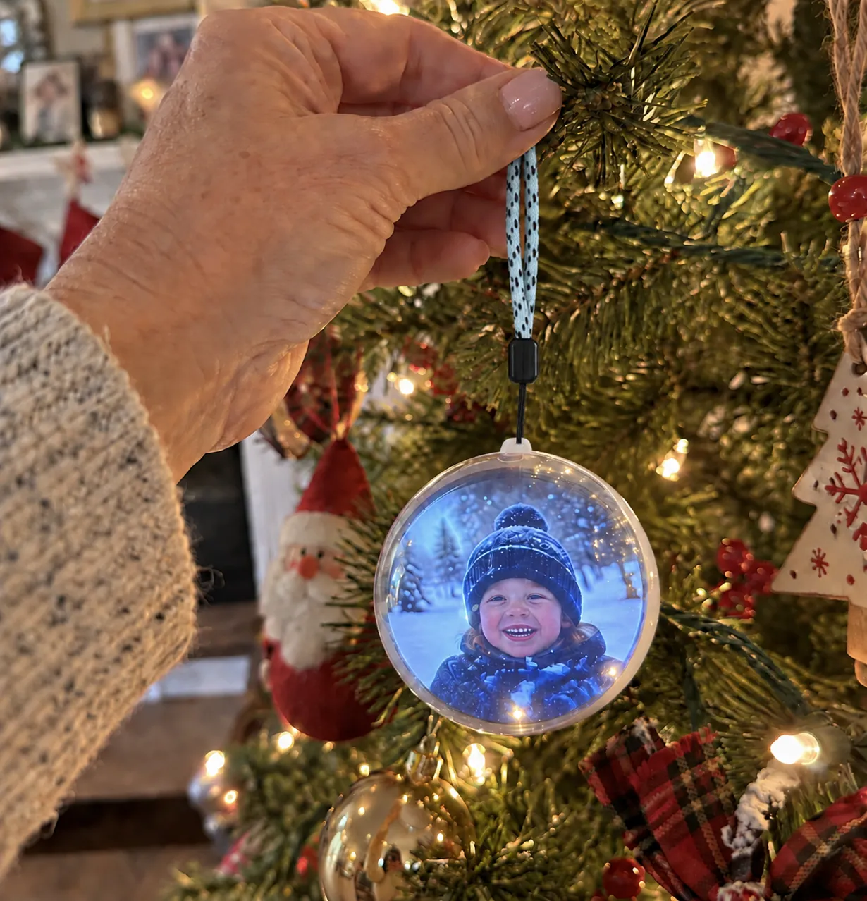 A hand hanging the video keepsake orb on a family Christmas tree