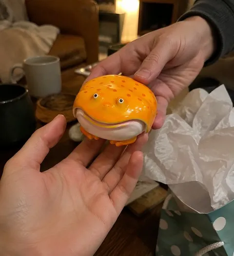 Yellow frog earbud case passed between friends as a gift