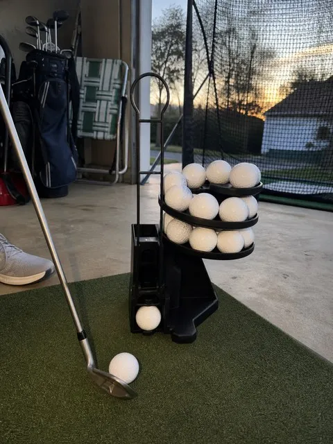 All black golf ball dispenser in a garage practice area