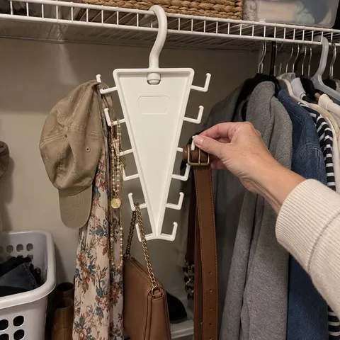 White V-shaped organizer holding a hat, scarf, jewelry, purse and belt in a small closet