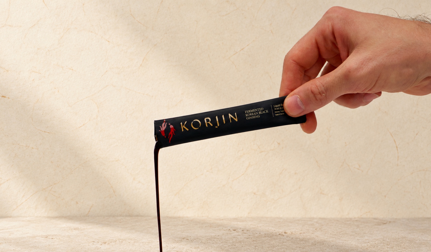 A hand squeezing a Korjin stick, the dark extract running out