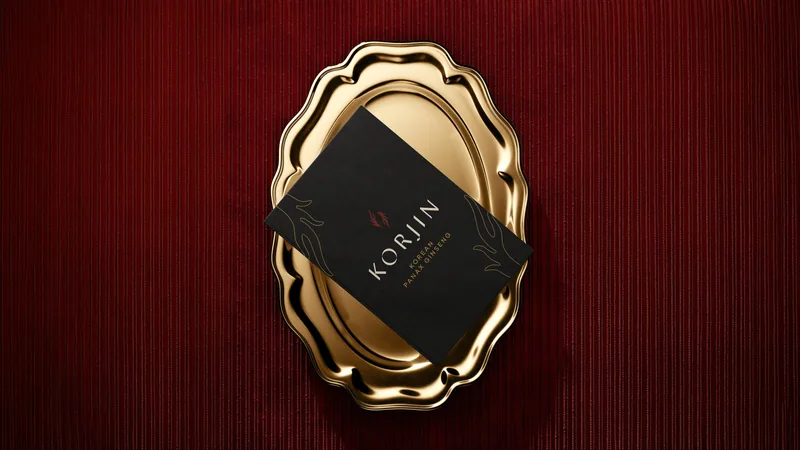A Korjin business card resting on a gold tray against red velvet