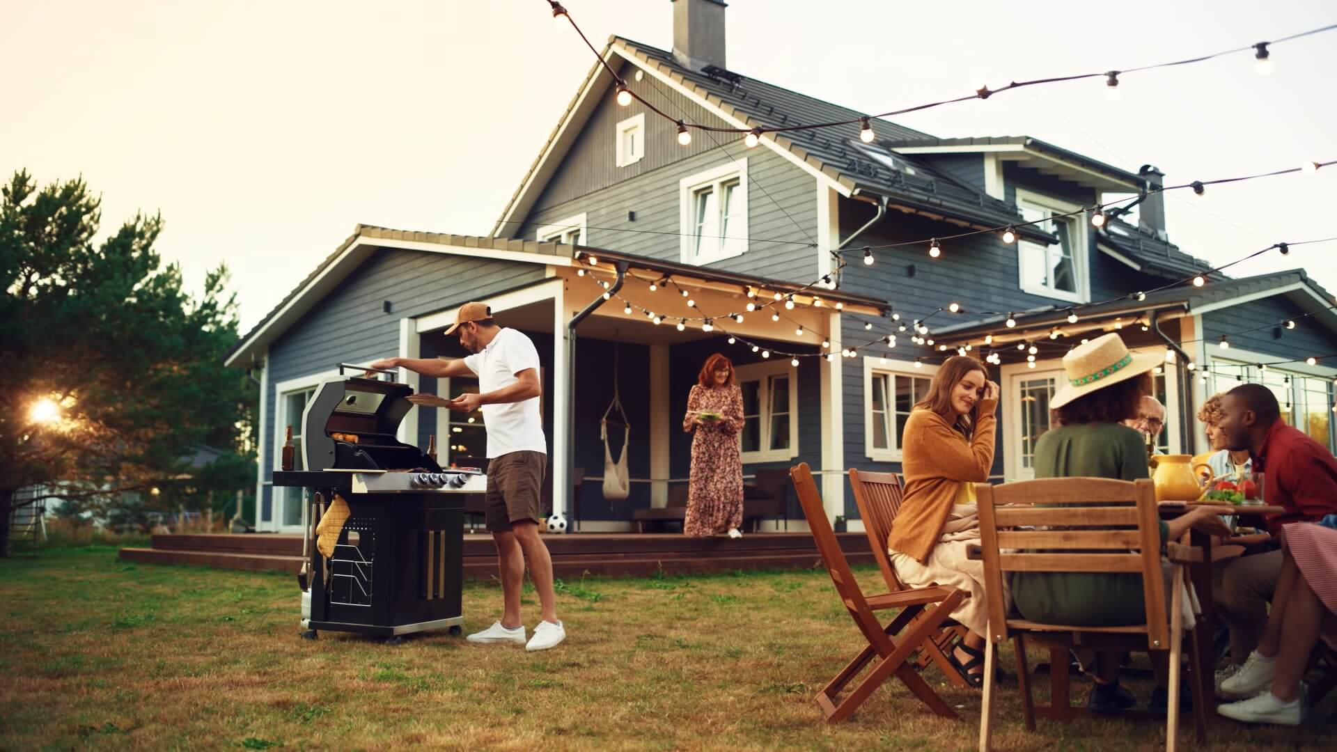 Adults enjoying a backyard barbecue at dusk