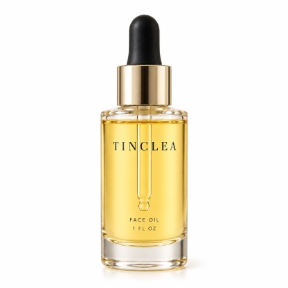 TinClea Face Oil, Face oils 1 fl oz clear glass dropper bottle with amber oil and champagne gold collar on a white background