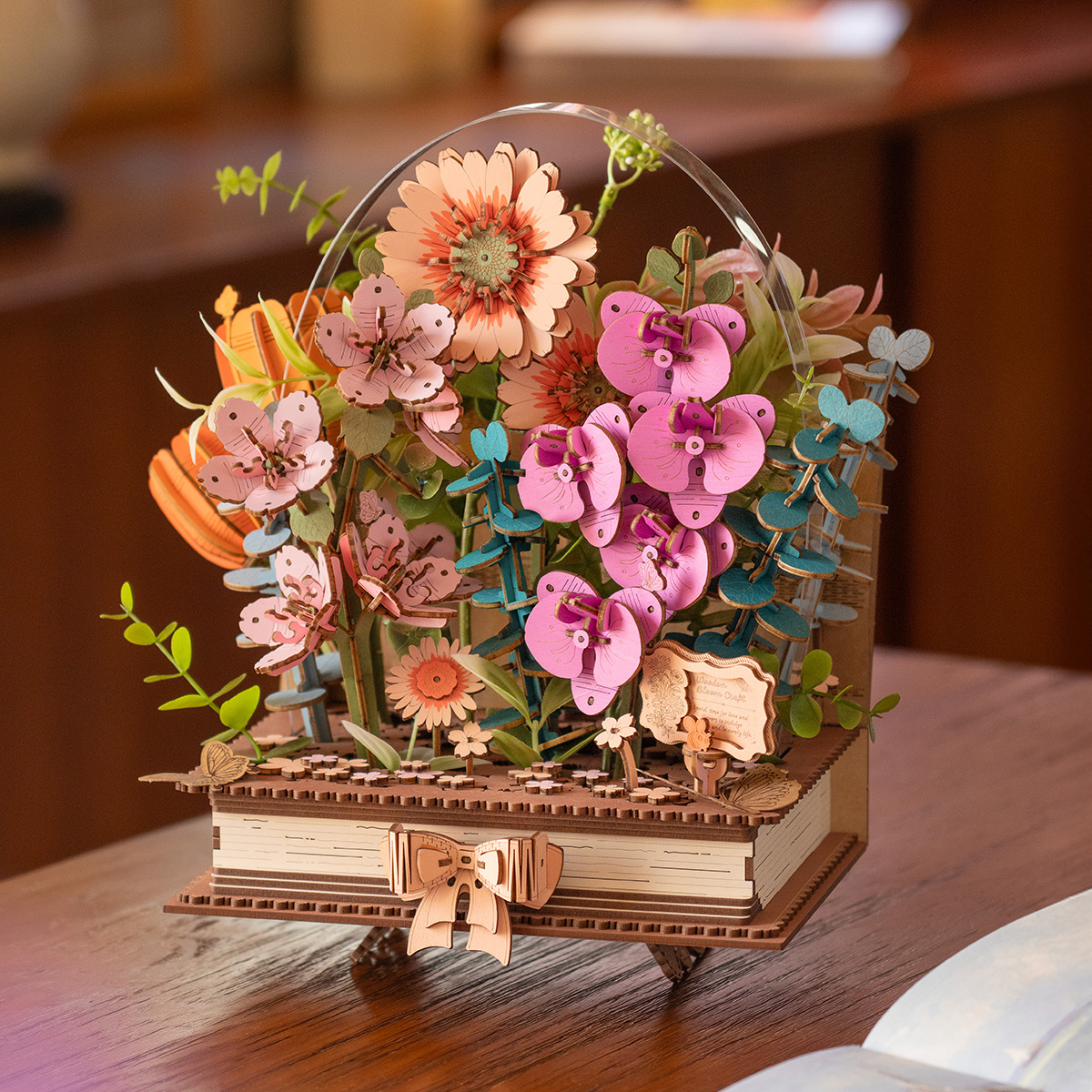 Bloeiend boek TW04H met kleurrijke houten bloemen en bladeren op een boekvormige voet, op een houten tafel