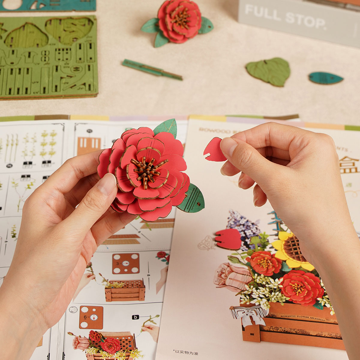 Mano montando una flor roja junto a las instrucciones — TW02H