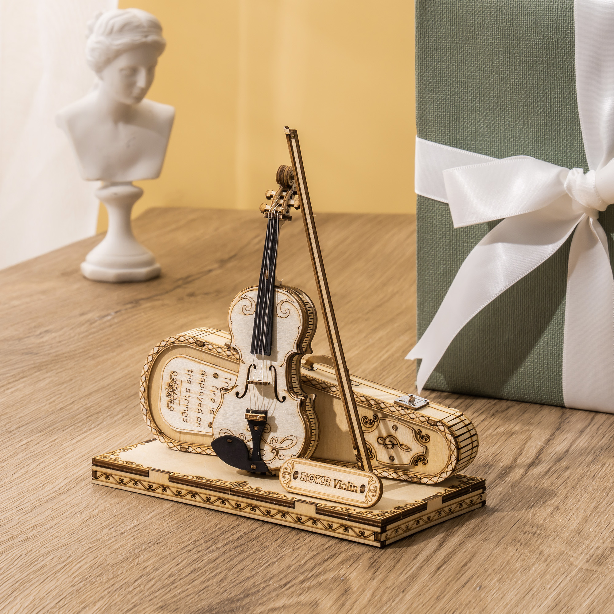 Violín junto a una caja de regalo y un busto decorativo — TG604K