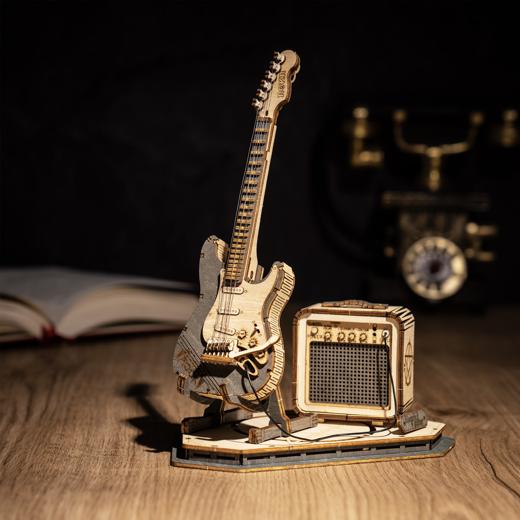 Guitarra de madera sobre un escritorio oscuro junto a un amplificador — TG605K