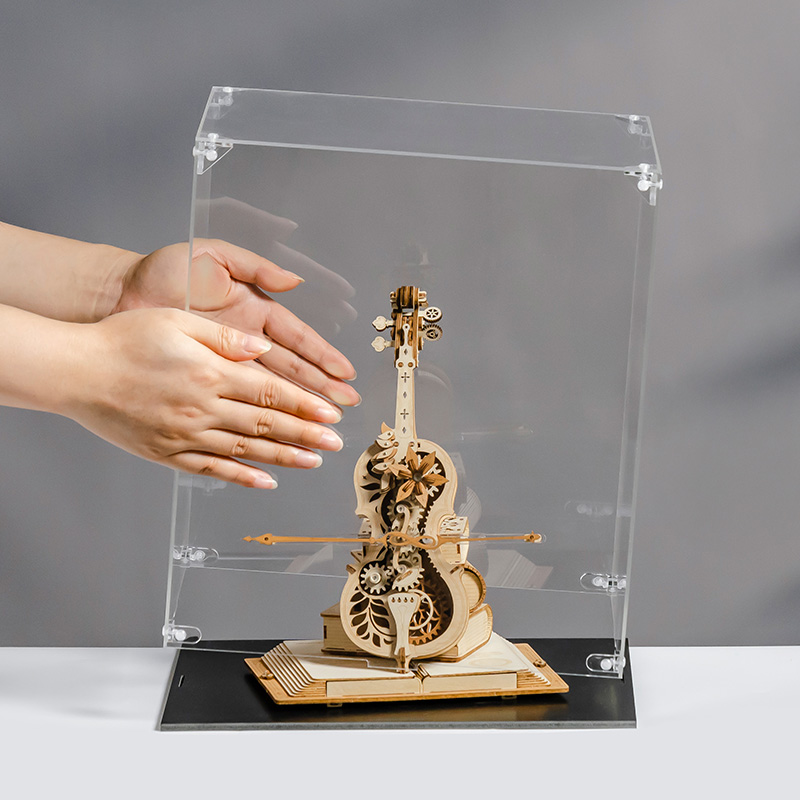 Manos colocando la cubierta transparente sobre una caja de música con forma de violonchelo — RFM04