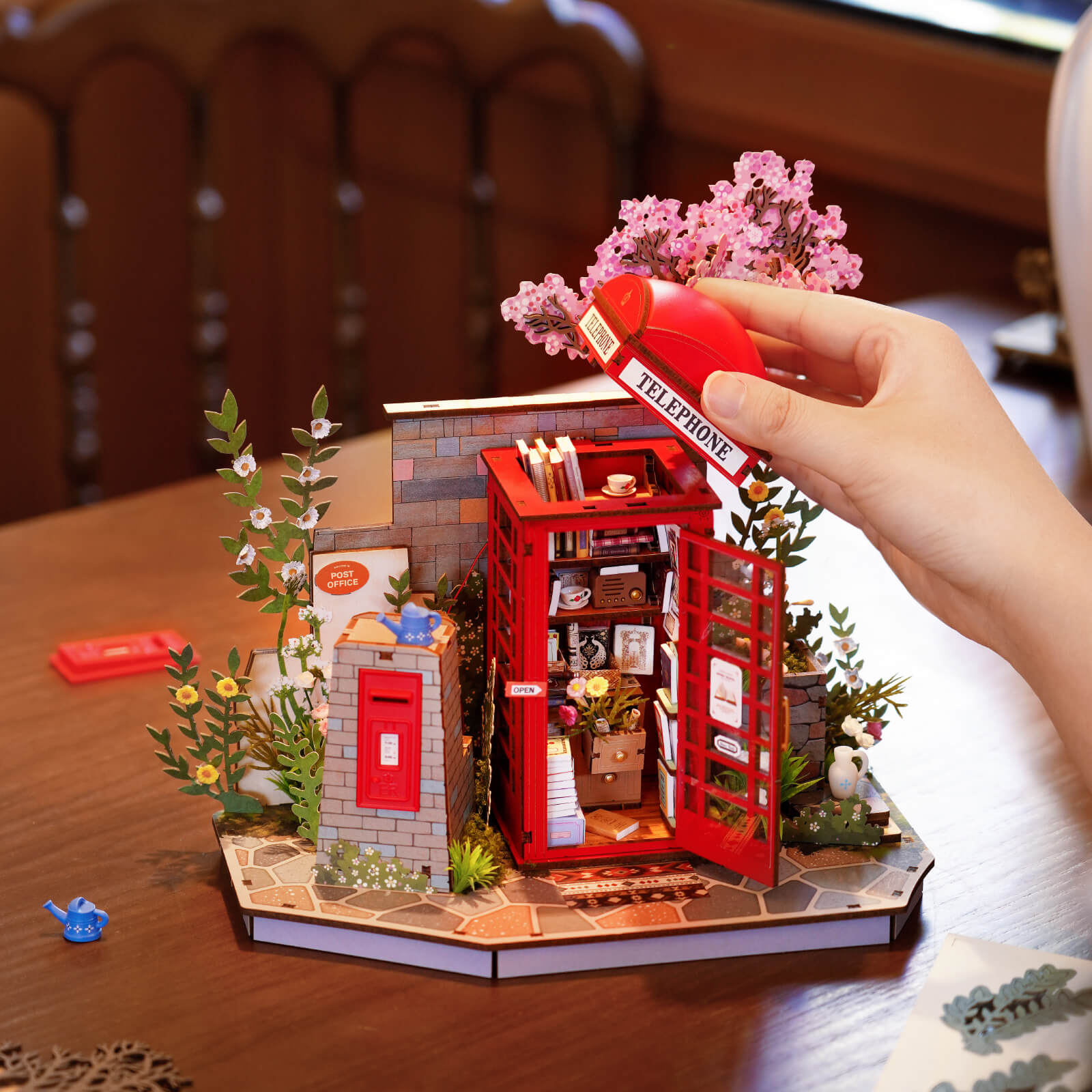 Hände legen Bücher hinein Blossom Book Booth rotes Telefonzellenmodell