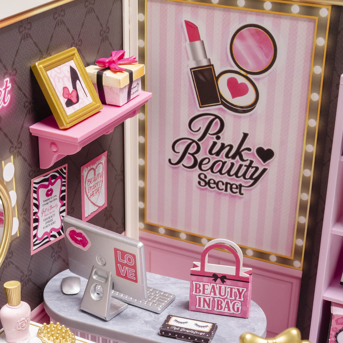 Nahaufnahme des Wandplakats „Pink Beauty Secret“, Regal, Laptop und Kosmetiktasche