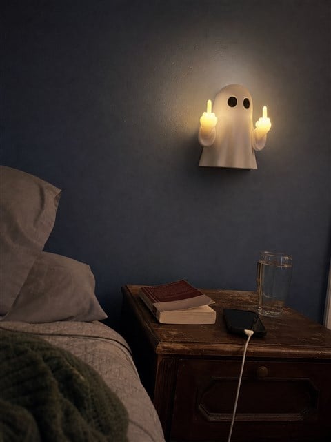 Ghost wall night light glowing above a lived-in bedroom nightstand
