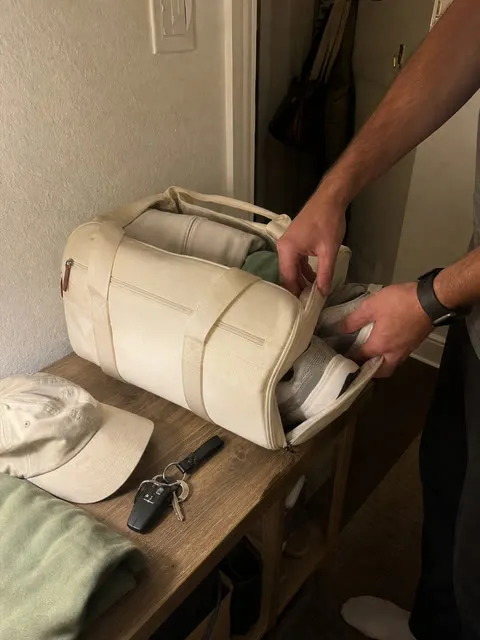 Sneakers being placed into the bag's separate shoe section