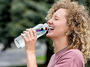 Woman enjoying Re-Lyte Hydration drink outdoors for clean, optimal, no sugar hydration support.