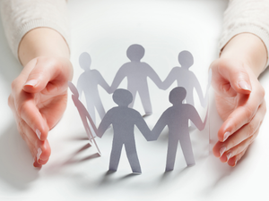 Hands surrounding paper figures representing care and wellness.