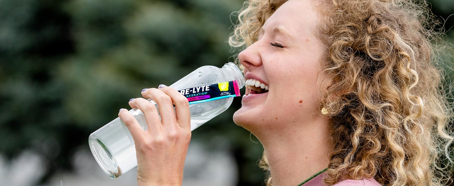 Woman enjoying Re-Lyte Hydration drink outdoors for clean, optimal, no sugar hydration support.