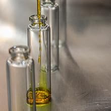 Small glass vials with olive oil being testing and dropped into them