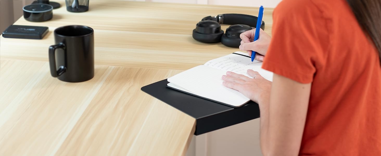 woman writing in notepad on corner desk