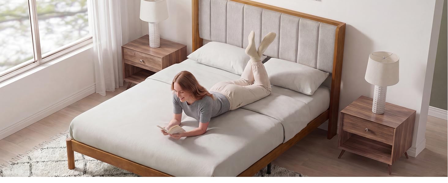 Person on the Zinus Jonas Bamboo Bed Frame in a bright bedroom with neutral bedding