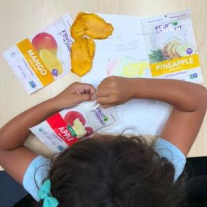 Young girl opening an organic dried apple snack pack while she colors