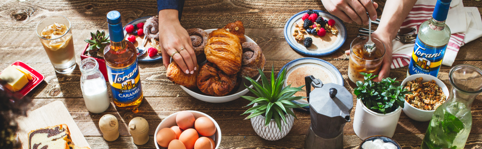 torani syrups bottles on a wooden table with brunch foods including coffee
