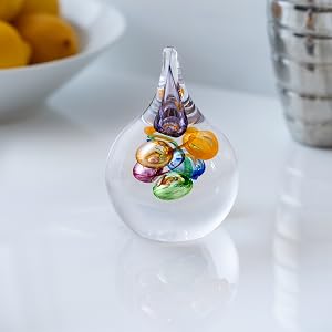 Series of decorative glass pieces or ornaments with colorful elements, photographed on a light surface with ambient lighting effects.