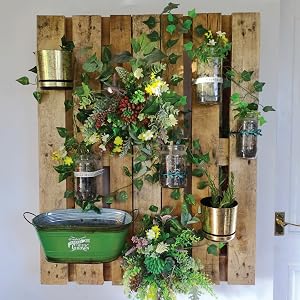 A vertical garden built on a wooden palette installed on a wall.