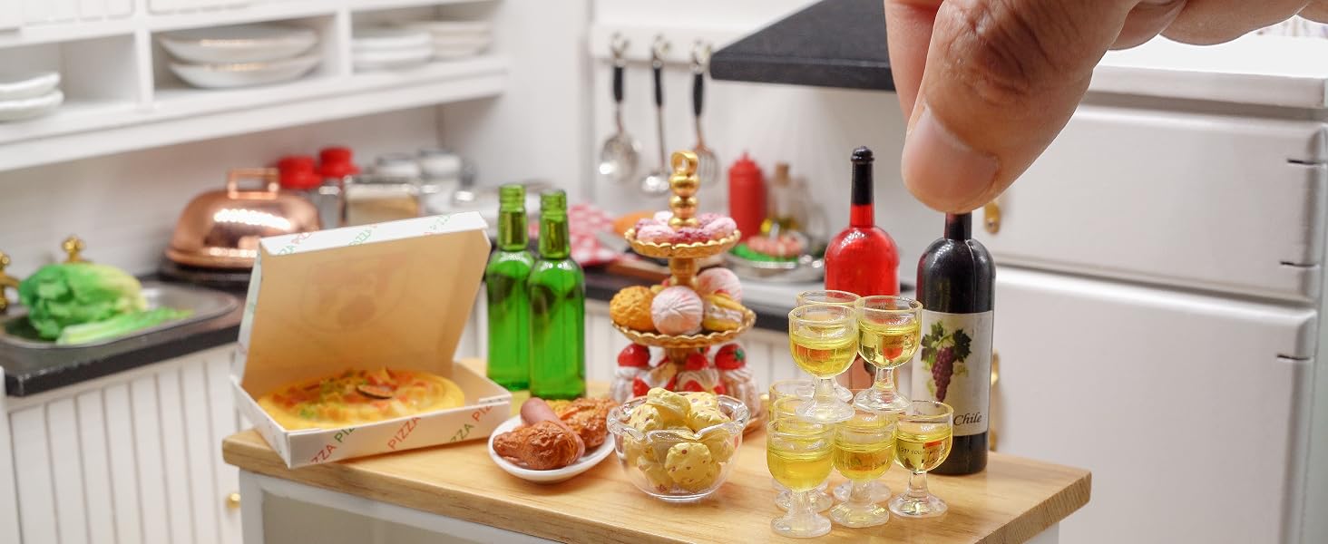 Kitchen counter with wooden tray holding miniature food items, bottles, and glasses. Hand reaching to interact with the small-scale display.