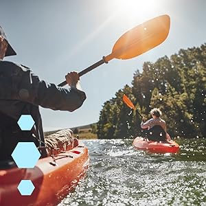 Two people in orange kayaks paddling down a river on a sunny day, trees in the background