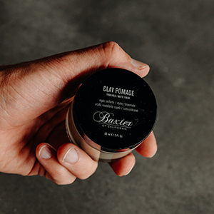 Man&amp;#39;s hand holding a jar of Clay Pomade